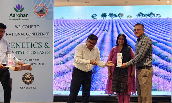 Three participants with a memento in front of the conference banners